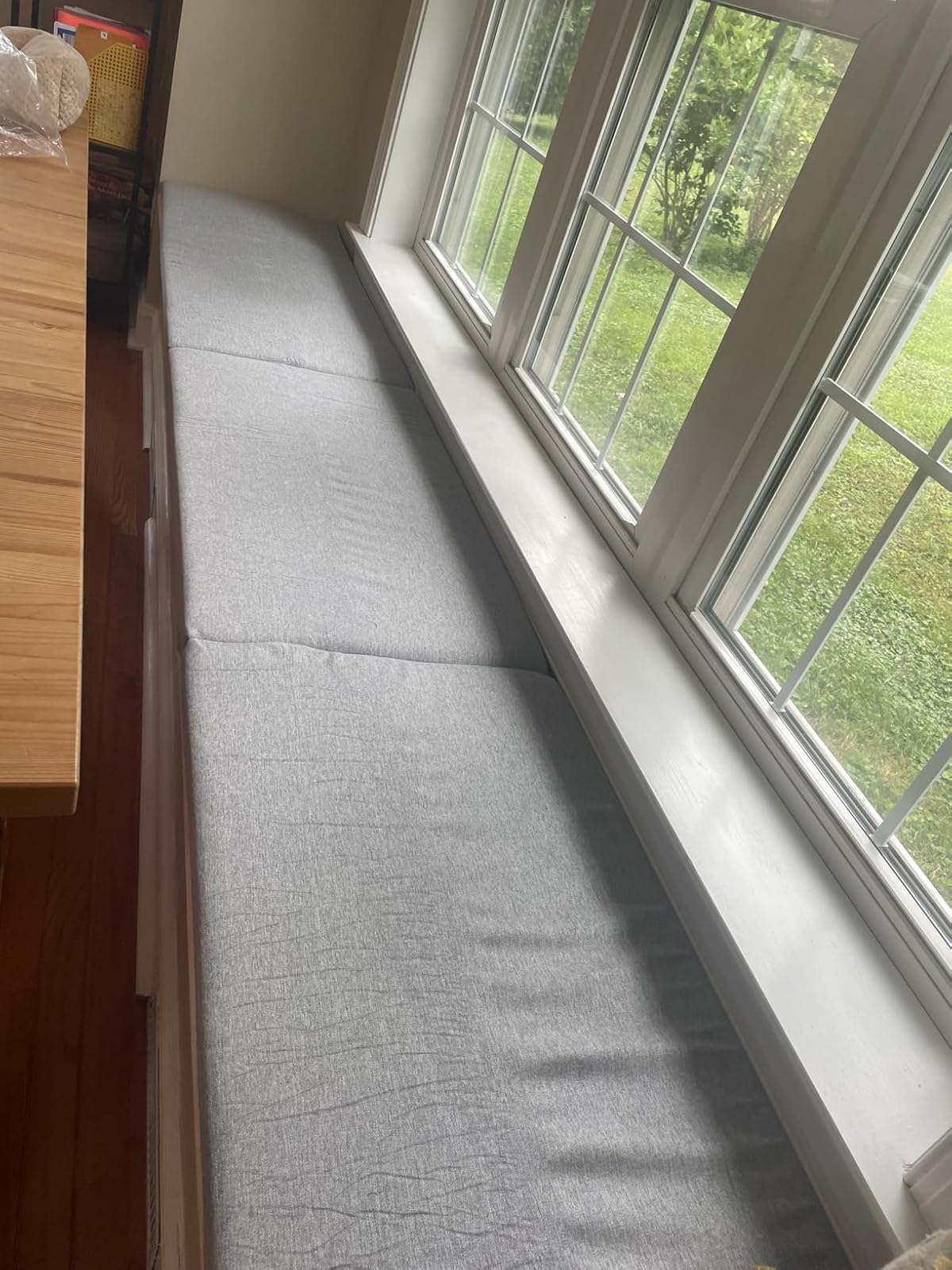 Custom gray bench cushion on wooden dining bench in bright kitchen